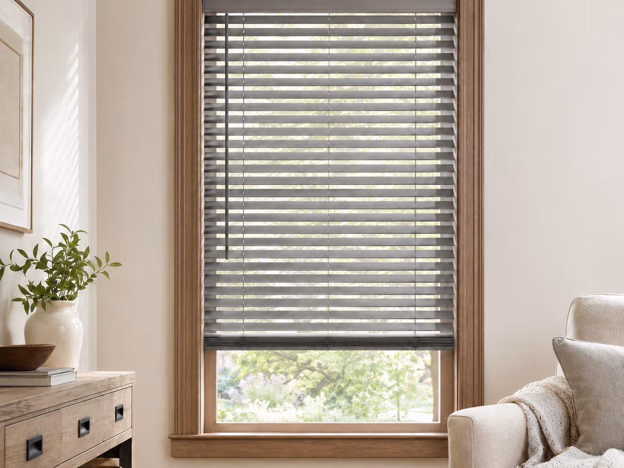 Wide driftwood-gray wood slats tilted open in a stained wood casing beside a living-room chair — Parkland Wood Blinds installed by Discount Best Blinds of Santa Rosa, CA.